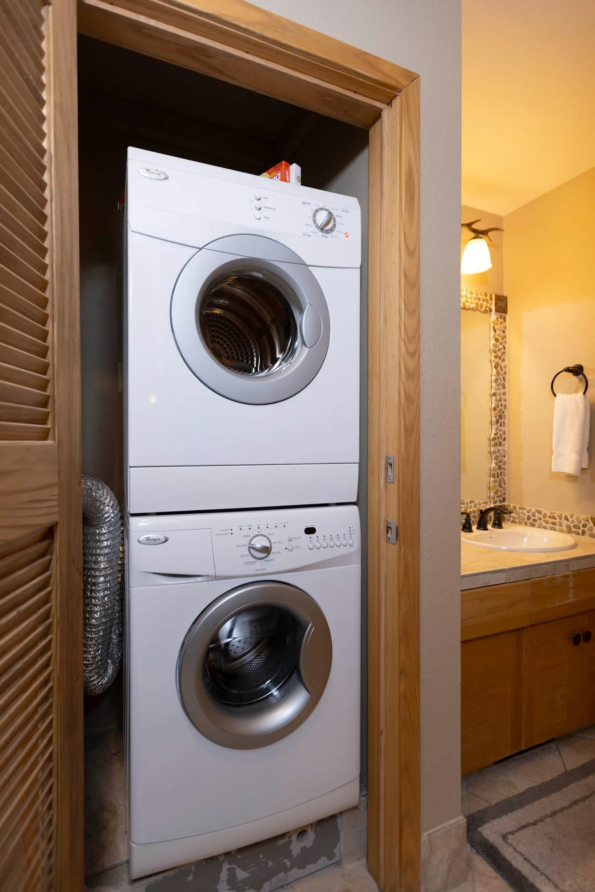 A neatly organized interior with a stacked washer and dryer next to a bathroom sink and mirror. The space feels practical and tidy, emphasizing the everyday conveniences available to guests.