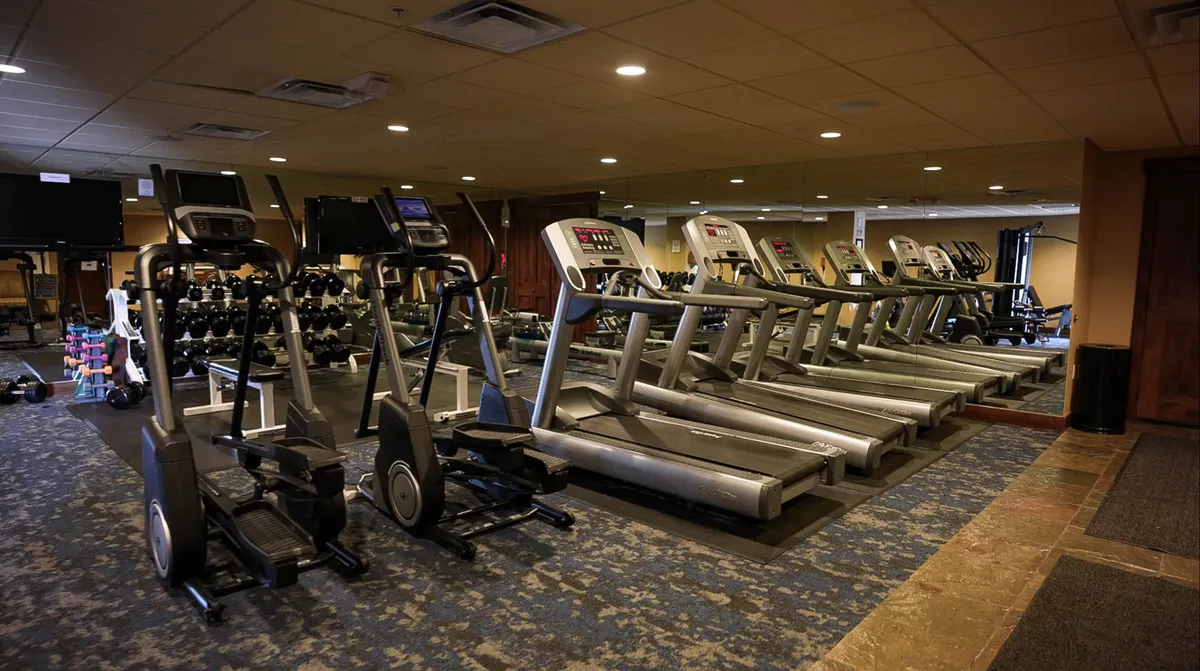 A modern, well-equipped fitness center featuring treadmills, ellipticals, free weights, and mirrored walls. The bright, motivating atmosphere encourages guests to keep up with their fitness routines while away from home.